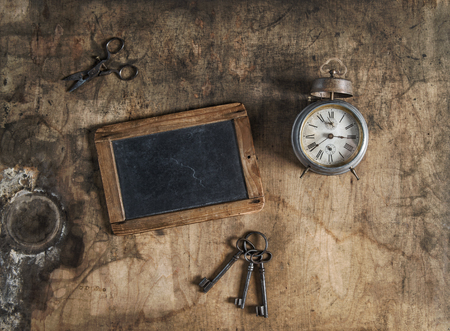 Rustic wooden background with vintage office accessories. Antique scissors, keys, alarm clockの写真素材