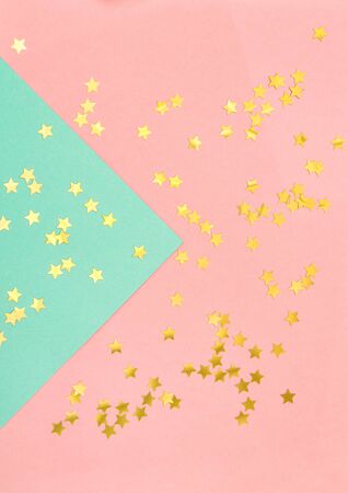 Star shaped golden confetti on pink blue flat lay backgroundの写真素材
