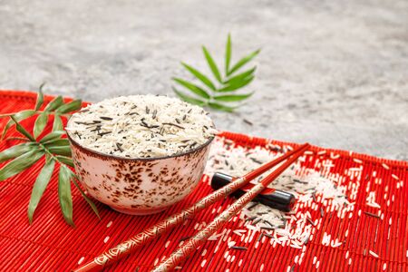 Rice with chopsticks on red bamboo mat background. Asian cuisine conceptの写真素材