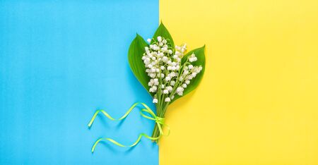 Lily of the valley flowers on yellow blue background. Floral flat layの写真素材