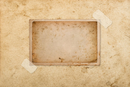 Used paper photo frame with tape strips on grungy background