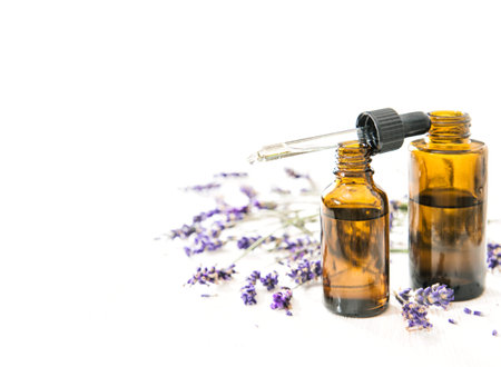 Herbal oil and lavender flowes on white background
