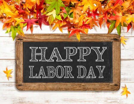 Happy Labor day. Autumn leaves and chalkboard on bright wooden backgroundの写真素材