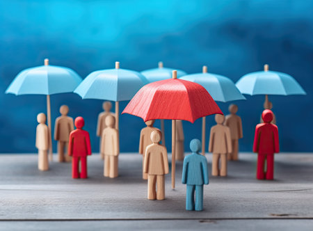 Red toy umbrella and wooden doll figures isolated on a blue background. insurance coverage conceptの素材