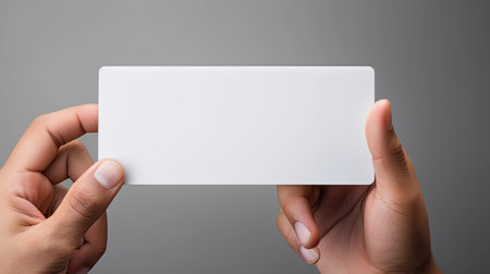 a man's hand holding a blank, simple white business card design mockup, the absence of text and the potential for business branding against a light backgroundの素材