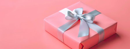 a pink gift box adorned with a silver ribbon, set against a soft pastel pink background, showcasing a minimalist concept in a flat lay viewの素材