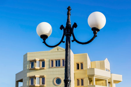 White round street lamps on a lamppost against  blue sky and yellow hotel building