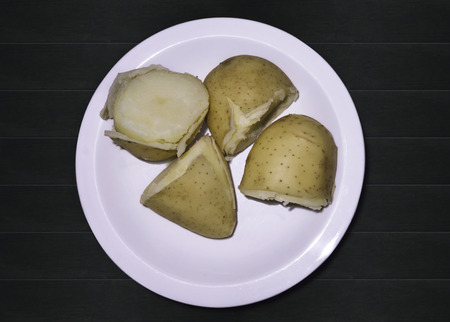 Boiled young potato in their skins on the plate on a green table. Top view, close upの写真素材