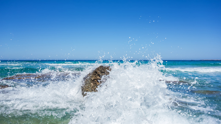 High sea waves with foam and spray breaking on rocksの写真素材