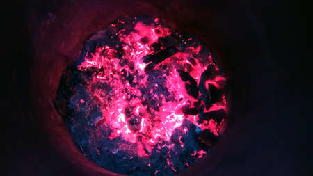 Burning embers at the bottom of a metal barrel.の写真素材