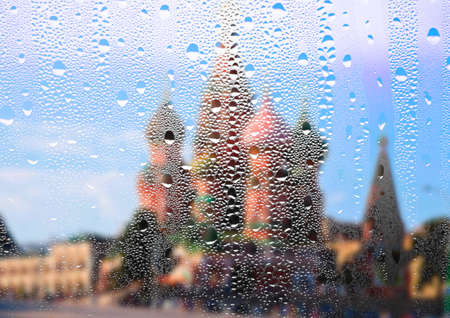 Drops of water run down the window glass. Wet glass texture. Condensation of the fog on the window with blurred background of the building. Summer rainy day. Raindrops on the glass. Misted background.の写真素材