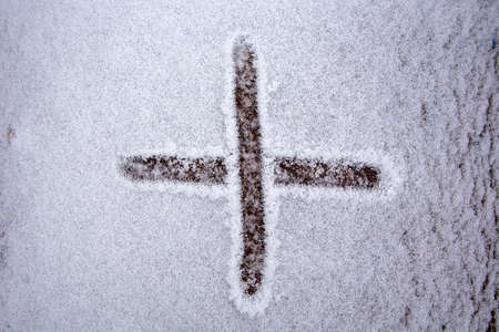 The plus sign is written on the snow. Snow signs of addition. Original winter drawing.の写真素材