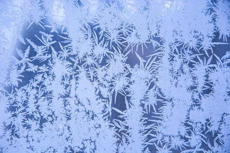 Snowy frosty pattern on a glass surface. Frost on the glass of the window. Frosty window. Snowflakes...