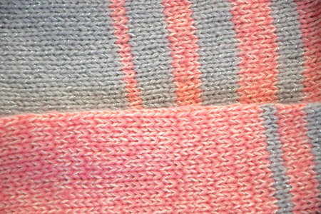 Knitted fabric. Knitted sweater. Pink jersey with gray stripes. Knitted texture of loops.