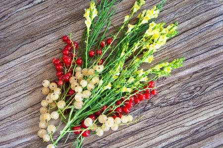 Bouquet of wildflowers with currant berries on a wooden background. Bright yellow flowers.