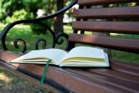 The book is on the bench. There is a diary on a wooden bench in the park.の写真素材
