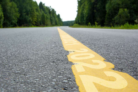 Yellow line markings with years mark. Asphalt road in the forest. Years change concept.の写真素材