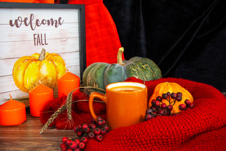 Halloween still life. Pumpkins, orange candles and a cup of pumpkin juice on a napkin.