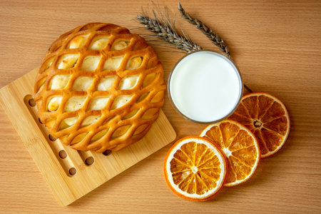Cheesecake with cottage cheese, orange slices and a glass of milk on a wooden background. Still life with food. Bakery.の写真素材