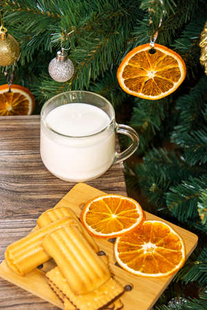 Christmas tree with dry orange slices. Cookies with milk for Santa Claus.の写真素材