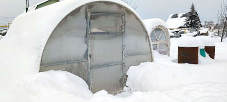 Polycarbonate greenhouse in winter. The greenhouse covered with snow. Sturdy greenhouse under the snow.の写真素材