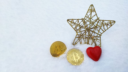 Christmas star and bitcoins lie on the snow. Cryptocurrency in the snow.