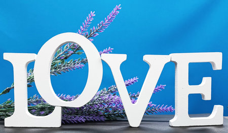 Word LOVE from letters on a blue background with lavender flowers