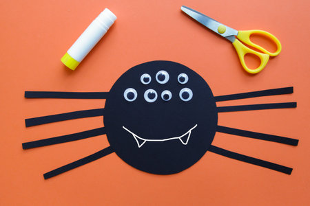 The child creates a black spider decoration. Halloween party. Children's art project. DIY concept....