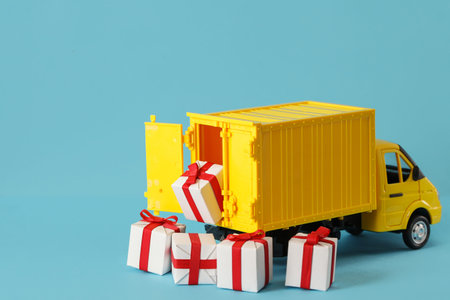 Yellow truck delivery gift box on blue background. Cargo transportation, delivery service. Transport...