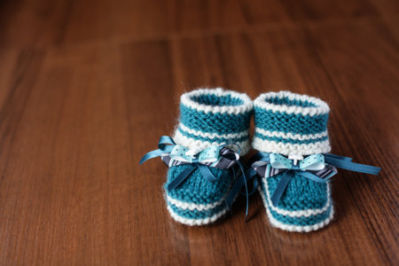 Comfortable hand-knitted childrens shoes on wooden background. Crocheted booties for newborns. preparation for birth and Motherhoodの写真素材
