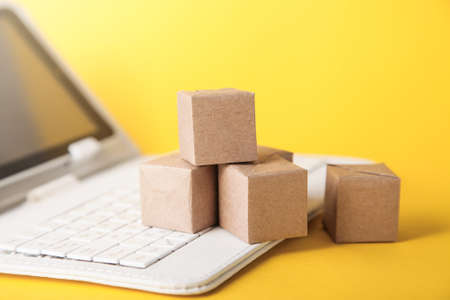 Online postal service. Cardboard boxes, keyboard on yellow background. Copy space. Delivery service concept.の写真素材