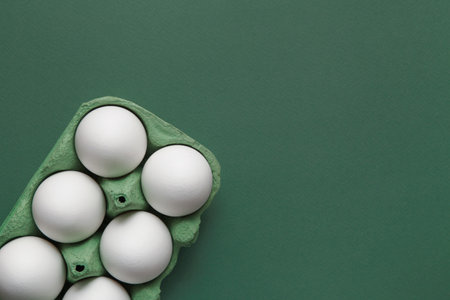 Minimal concept Easter. White Eggs in cardboard box on green background. Copy spaceの写真素材