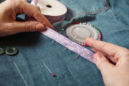 Woman sewing tape at jeans material. Handmade, authentic lifestyle