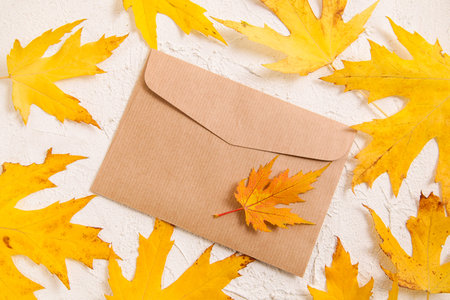Empty brown craft envelope, autumn leaves on white background. Copy spase