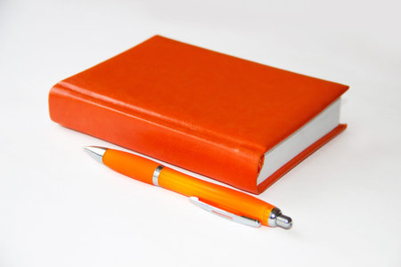 Red notebook and pen on a light backgroundの写真素材
