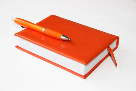 Orange notebook and pen on a light backgroundの写真素材