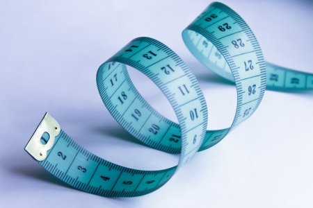 A coiled blue-green measuring tape on a light backgroundの写真素材
