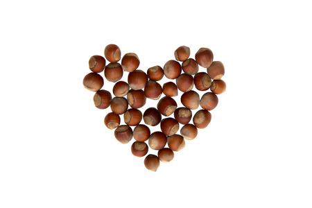 The heart shape by hazelnut isolated on a white の写真素材