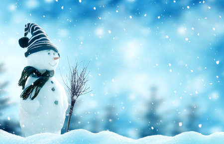 Greeting card with copy-space. Happy snowman with a broom standing in winter landscape. Snow background. Winter fairytale.の写真素材