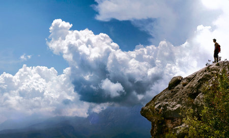 Man staying on a top of a rock in the cloudsの写真素材