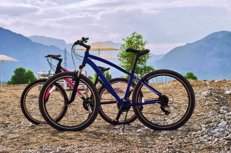 Two bicycles standing on the beach at mountains backgroundの写真素材