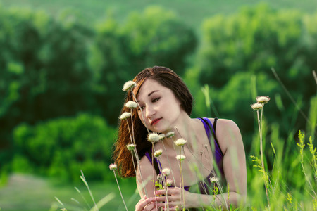 Young woman with long hair in field among flowersの写真素材