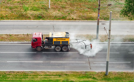 Orenburg, Russia-July 07, 2016: Worker is repairing road potholes with asphalt emulsion by Madpatcher machineのeditorial素材