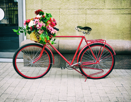 Red bicycle with floral basket lean against the wall in the street. Retro old-fashioned styleの写真素材