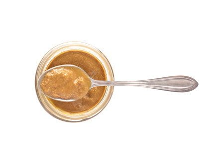 Spoon with nut butter or sesame paste tahini on glass jar. Food ingredient isolated on white backgroundの写真素材