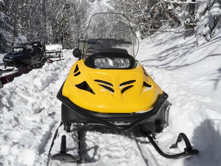 Front view of yellow and black snowmobiles on snow at winter sunny dayの写真素材