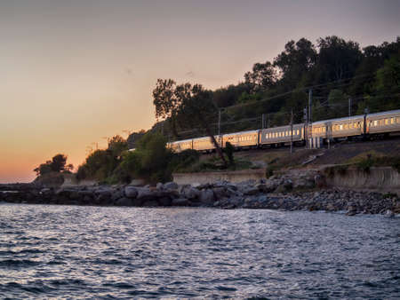 Train on railway along sea coast at sunset backgroundの写真素材