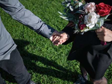 Top view of man and woman with bouquet of flowers holding hands. Closeup of couple in love or just marriedの写真素材