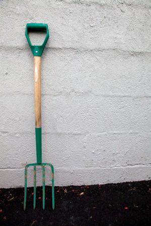 A well used pitchfork leaned against a concrete wall.の写真素材
