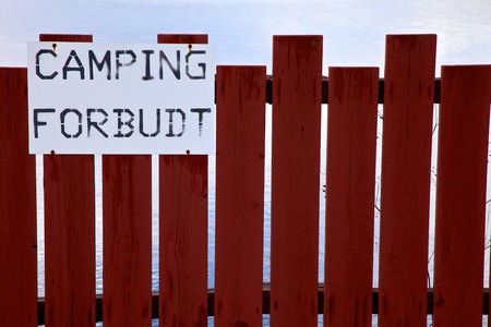 No camping sign on a wodden fence near the water.の写真素材